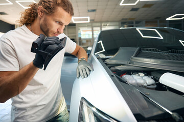 Young man inspects the car body covering