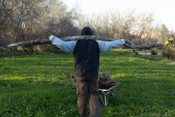 Persona llevando un tronco de leña encontrado en el río 
