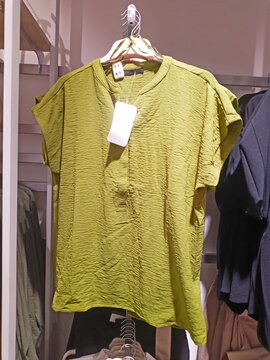 green blouse hanging on a hanger in a boutique