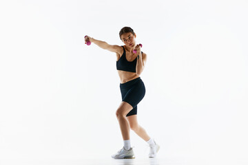 Young woman with slim sportive body training, doing jab exercises with dumbbells isolated over white studio background. Concept of sport, health and body care, fitness app, exercises templates - obrazy, fototapety, plakaty