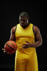 Vertical portrait of African American basketball player with ball against black background