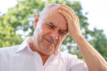 senior, mature man 50-55 years old holds on to head, close up male face with facial expression...