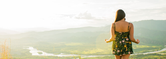 joven mujer de espaldas mirando el paisaje de atardecer en al montaña 