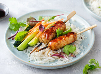 Delicious Asian-style chicken kebabs with rice, vegetables and teriyaki sauce, close-up.