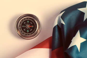 Compass pointing west and star spangled flag United States America.