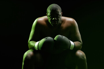 Dramatic backlit portrait of muscular African American boxer looking at camera with green outline