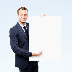 Image of business man showing advertise mock up sign board, empty banner with copy space area for ad slogan text, isolated grey background. Businessman hold blank white paper signboard.