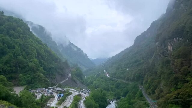 Storm clouds over mountains of Jang town deep in the  jang valley in tawang district of arunachal pradesh and surrounded by high mountains on a bright morning rainy day in arunachal pradesh in India.