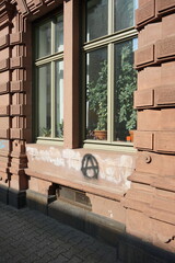 Altbau mit Fassade aus rotem Sandstein und großem Blumenfenster mit Zimmerpflanze im Sonnenschein und Graffiti in der Schulstraße im Stadtteil Sachsenhausen in Frankfurt am Main Hessen