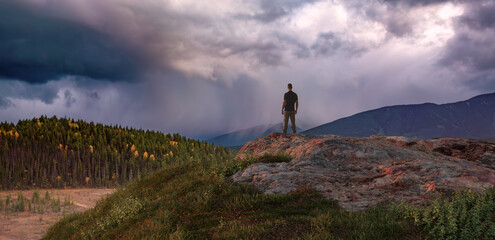 Adventure man hiker standing on top of Mountain Rock. Canadian Nature in Background Composite
