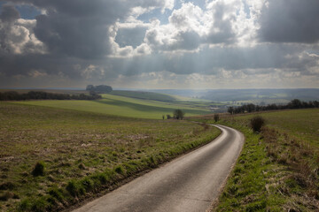 Empty single track country lane running down through open farmland with dramatic sky above, School Lane, East Garston, Berkshire, England, United Kingdom, Europe