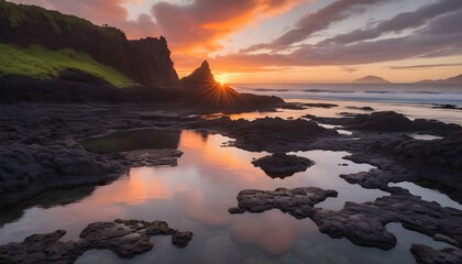 The ancient lava rock formations stand as silent sentinels against the backdrop of the setting sun. Pockets of tide pools teem with life, their crystal-clear waters reflecting the fiery sky. - obrazy, fototapety, plakaty