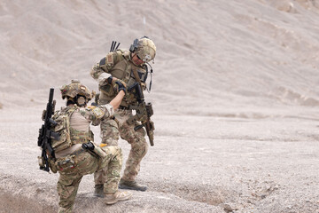 Soldier  giving hand and helping his mate to climb the mountain