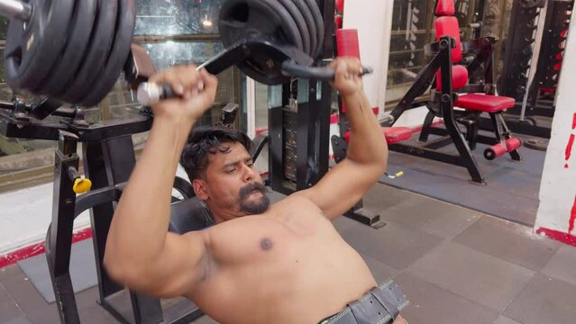Focused man performing bench press workout in a gym setting gym motivational video men with mustache