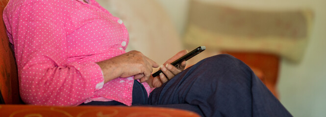 mujer mayor sentada escribiendo un mensaje de texto en el celular 