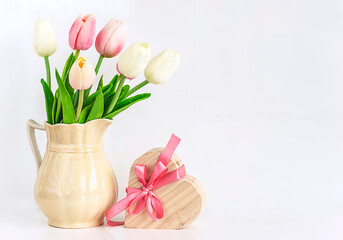 Happy international women's day or birthday concept; bouquet of wihte and pink tulips and heart shape gift box with pink bow on a white background with space for text