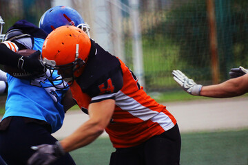 An American football player in an orange and black uniform with the number 54 blocks an opponent...