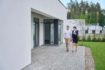 Fototapeta premium Woman realtor and client inspect the outside of new house