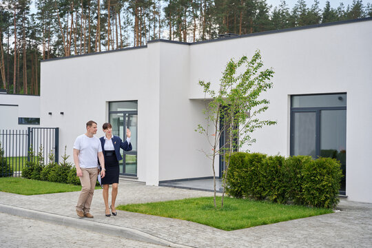 Buyer and sales manager walk through yard of new house