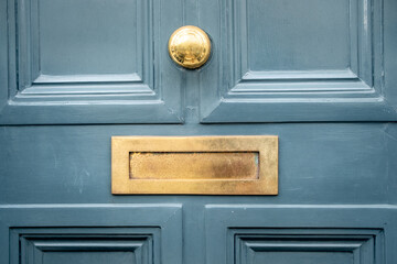Brass letter box on green door of British house