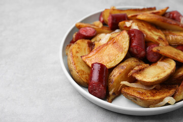 Delicious baked potato with thin dry smoked sausages and onion on gray table, closeup. Space for text
