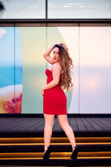 Beautiful young woman in red dress posing in the city streets