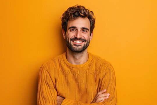 A man in a yellow sweater is smiling and posing for a picture