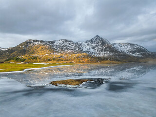 Reflective waters and rugged peaks create a dramatic natural scene in this mountainous winter terrain.