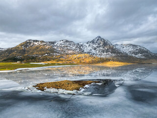 Reflective waters and rugged peaks create a dramatic natural scene in this mountainous winter terrain.
