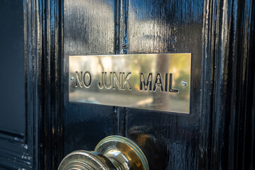 No Junk Mail sign on black British residential door.