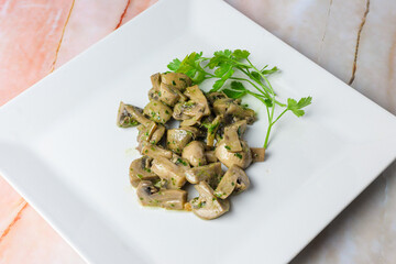 Herb-marinated mushrooms with parsley on a square white plate, typical food, typical mediterranean mallorcan cuisine typical from balearic islands mallorca, spain