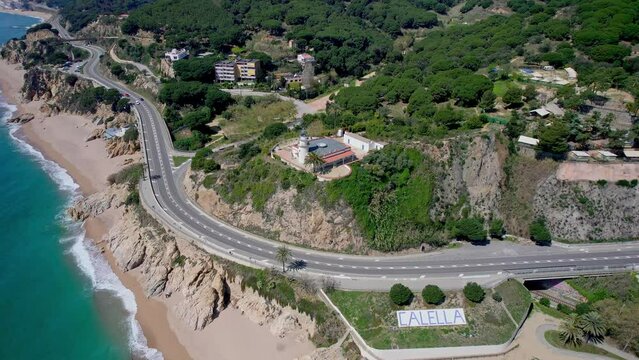 V&iacute;deo a&eacute;reo con dron de un faro sobre una monta&ntilde;a frente a una playa. Hermosa vista del mar y balneario de la costa de Barcelona