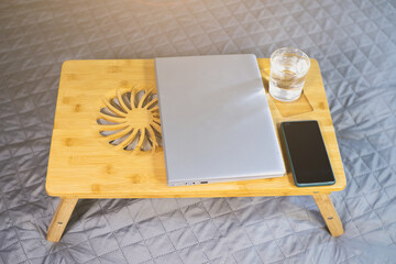 Laptop, smartphone and glass of water on the wooden Cooling pad for laptop. Notebook Cooler for Computer, USB Fan.