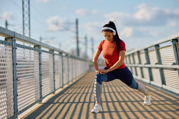 Athletic woman doing stretching exercise during sports training outdoors.