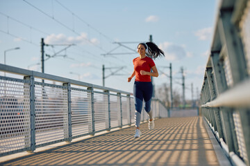 Young happy sportswoman jogging outdoors.