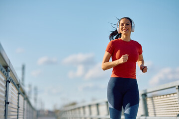 Happy athletic woman jogging during her sports training outdoors.
