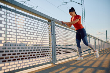 Female athlete using power band while doing leg exercises outdoors.