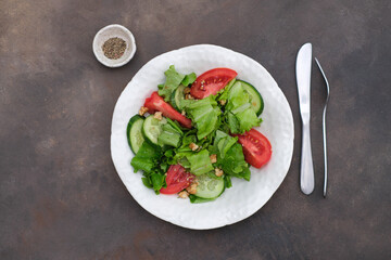  Vegetable salad - tomatoes, cucumbers, salad on white plate on dark brown background. Healthy Eating. Diet Concept. A Healthy Way Of Life. To Cook At Home. For Cooking. 