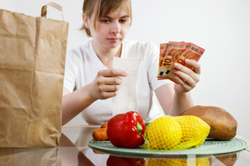 woman is leaning on the kitchen counter, checking the contents of her burlap bag which is filled...