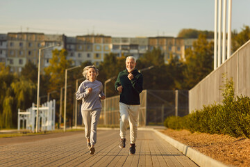 Active senior pair enjoy running, sporty physically energetic older man and woman outdoor jogging....