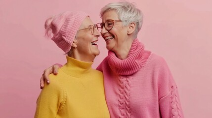 Two elderly homosexual women smiling at each other on a pink background - obrazy, fototapety, plakaty