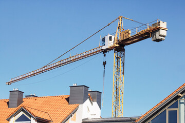 Crane background. Yellow paint heavy machinery equipment isolated on blue sky. Construction site view. Industrial building process. Block of flats in progress. Process of building.