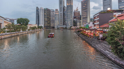 Singapore quay with tall skyscrapers in the central business district on Boat Quay day to night...