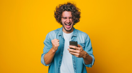 an exuberant young person with curly hair, holding a smartphone and seemingly shouting or cheering with a bright yellow background - obrazy, fototapety, plakaty
