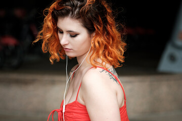 Portrait of caucasian woman using wired headphones outdoors.