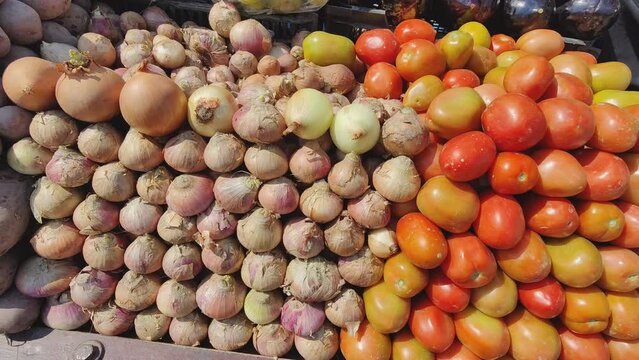 Fresh red tomatoes and onions on the stall. Lots of red tomatoes and onions at a vegetable shop in Pakistan. The seller displayed many fresh vegetables at the stall market. 4K footage.