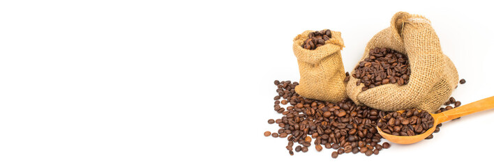 Open burlap bags scattered with whole coffee beans on a white background. Banner.