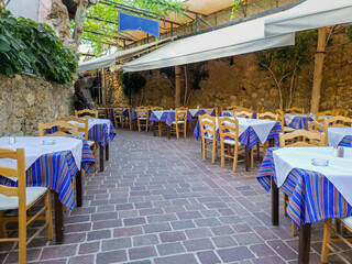 Open air traditional taverna at Chania Old Town Crete island Greece. Empty chair table, paved alley.