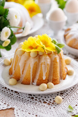 Bundt cake, Babka covered with icing, decorated with chocolate eggs and primrose flowers, close up view. Traditional Easter bundt cake