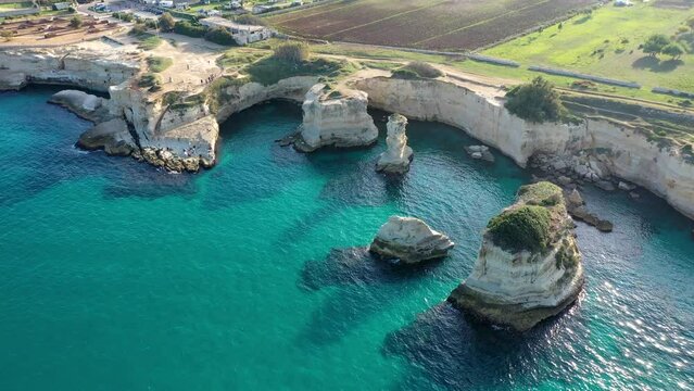 Stunning seascape with cliffs rocky arch and stacks (Faraglioni) at Torre Sant Andrea, Salento coast, Puglia region, Italy. Beautiful cliffs and sea stacks of Sant'Andrea, Salento, Apulia, Italy